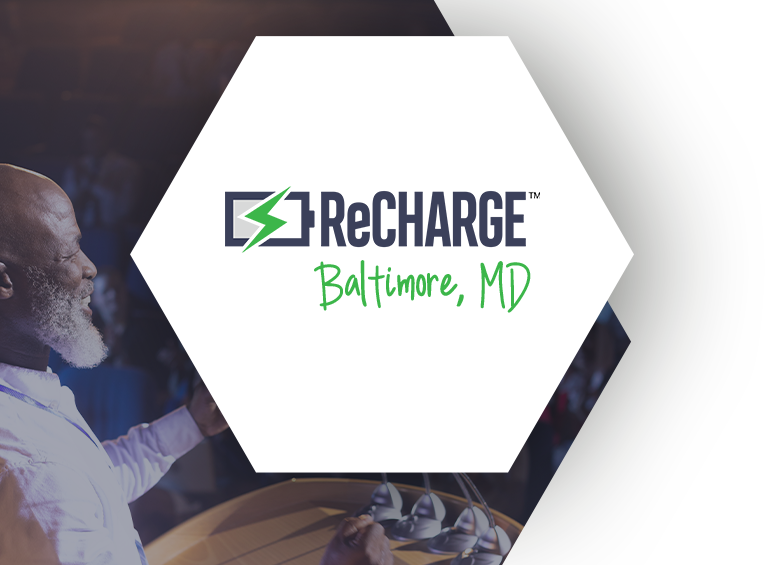 ReCharge Baltimore, MD logo in a hexagonal shape over a background of a speaker addressing an audience.